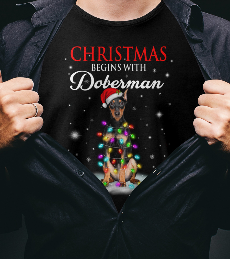 Christmas Begins With Doberman Wrapped In Holiday Lights And Santa Hat Snowflakes T-Shirt